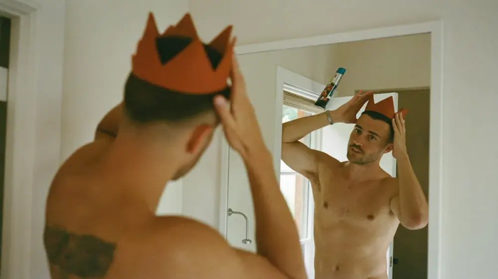 Hombre haciéndose una foto de la coronilla en el espejo con el móvil para hacer seguimiento de su pelo