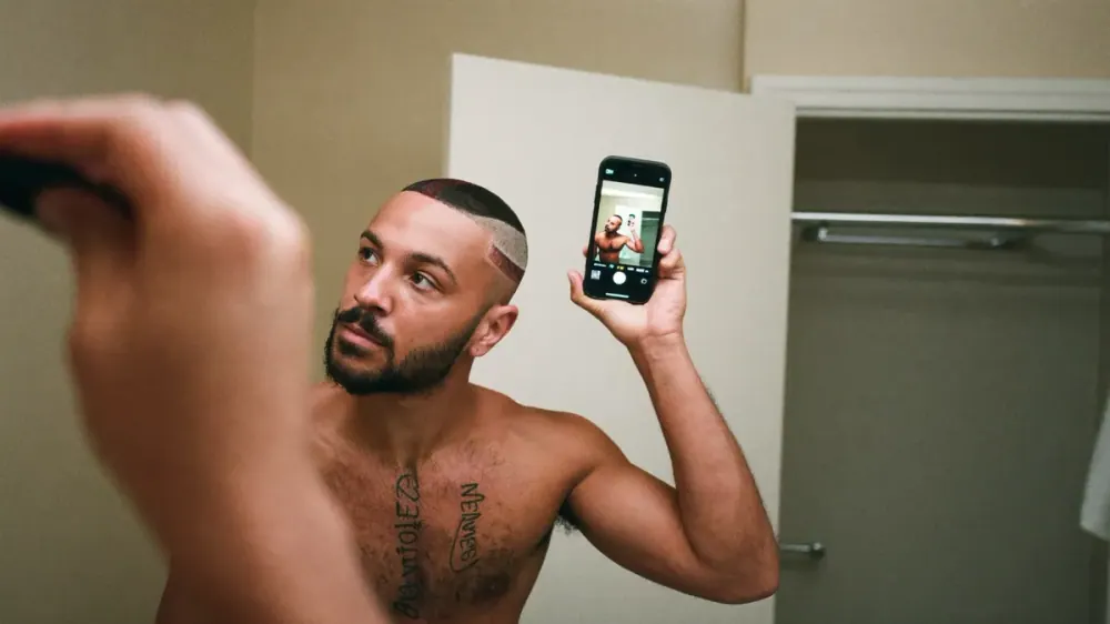 Hombre haciéndose una foto mensual del nacimiento del pelo frente al espejo para seguir la evolución de su caída